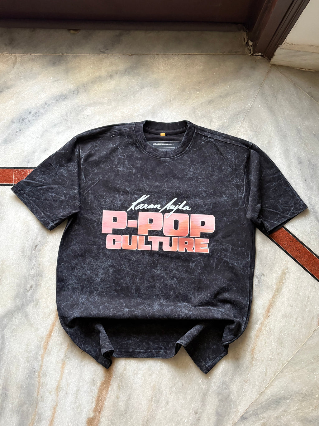 Black t-shirt with 'P-Pop Culture' text on a concrete floor