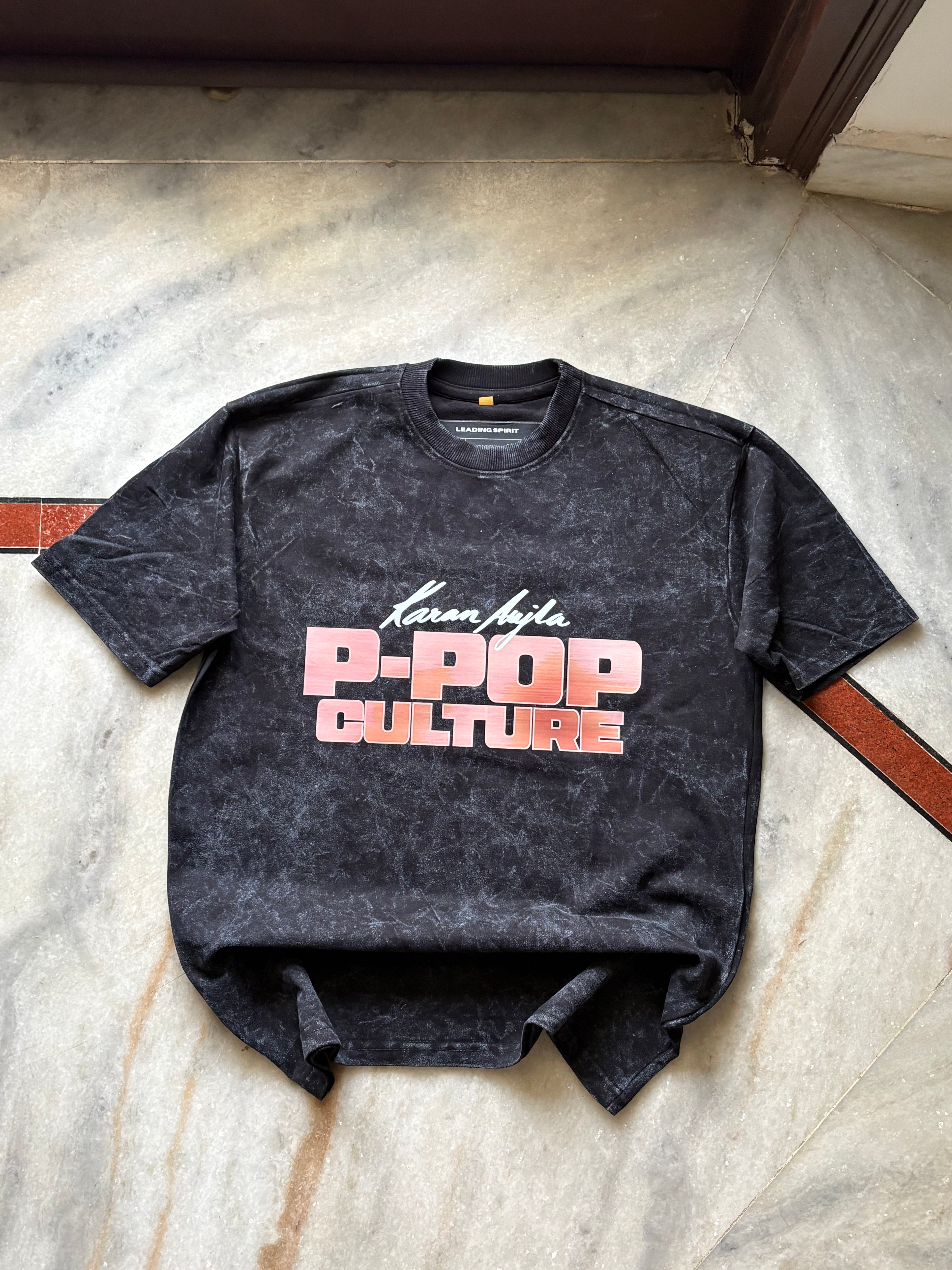 Black t-shirt with 'P-Pop Culture' text on a concrete floor